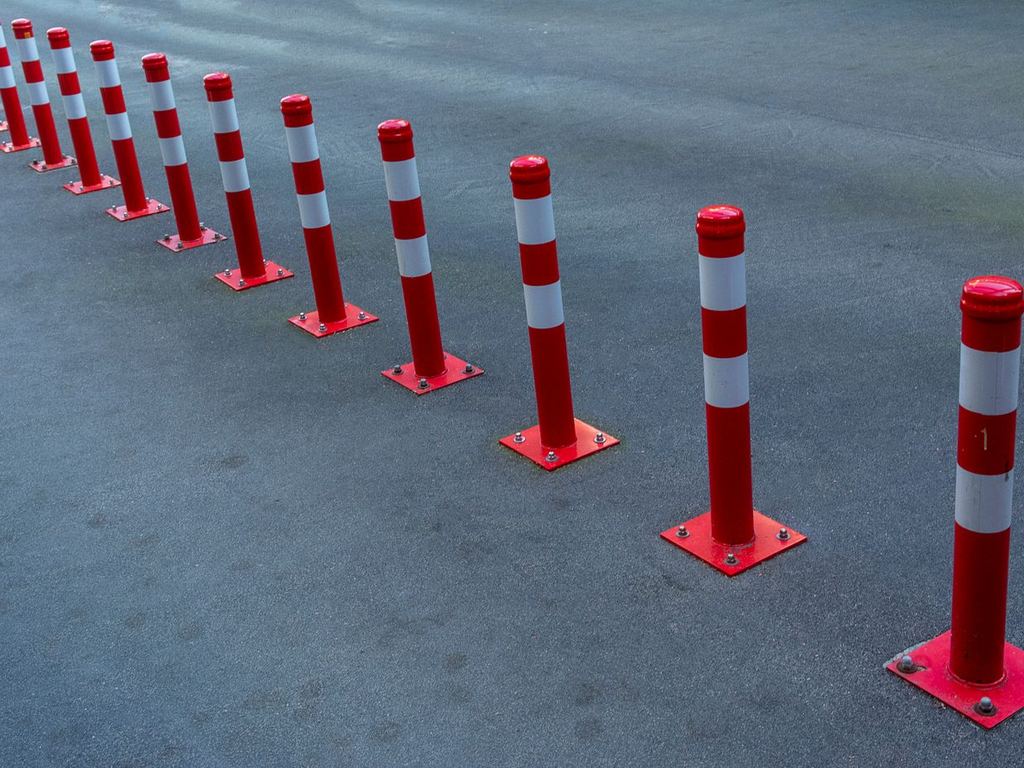 Line of red and white traffic bollards on pavement