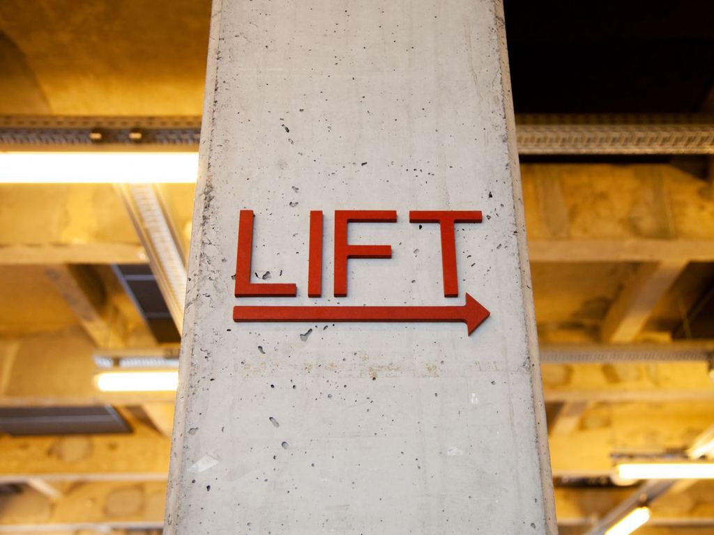 Directional sign with arrow on a concrete column inside a commercial building