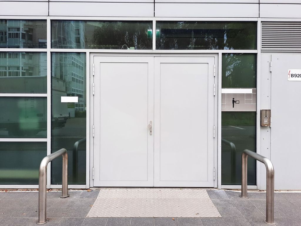 Modern commercial building entrance with double doors and steel bollards