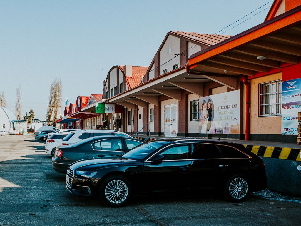 Row of retail storefronts with signs and a parking lot